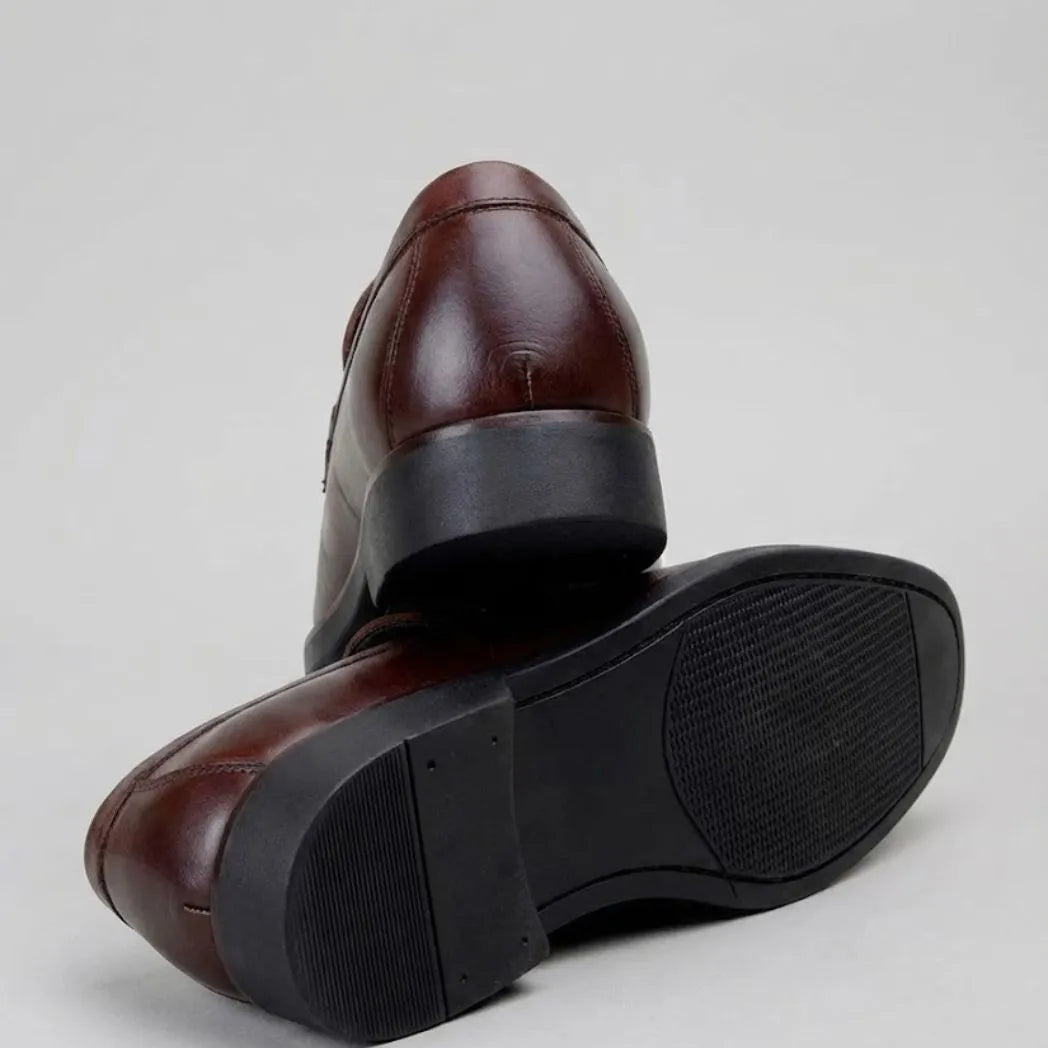 Mocassim Masculino Genova Loafer Couro: par marrom-escuro com um sapato virado, mostrando a sola preta.