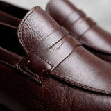 Mocassim Masculino Genova Loafer Couro: detalhe da textura marrom-escura, da faixa frontal e da costura.