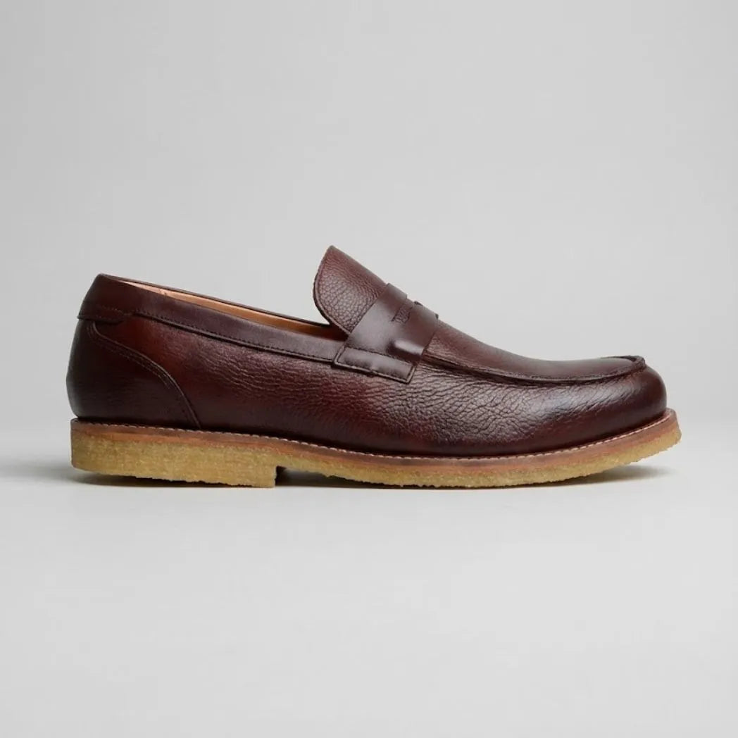 Mocassim Masculino Loafer Atenas: modelo marrom-escuro de perfil, com faixa frontal e sola bege.