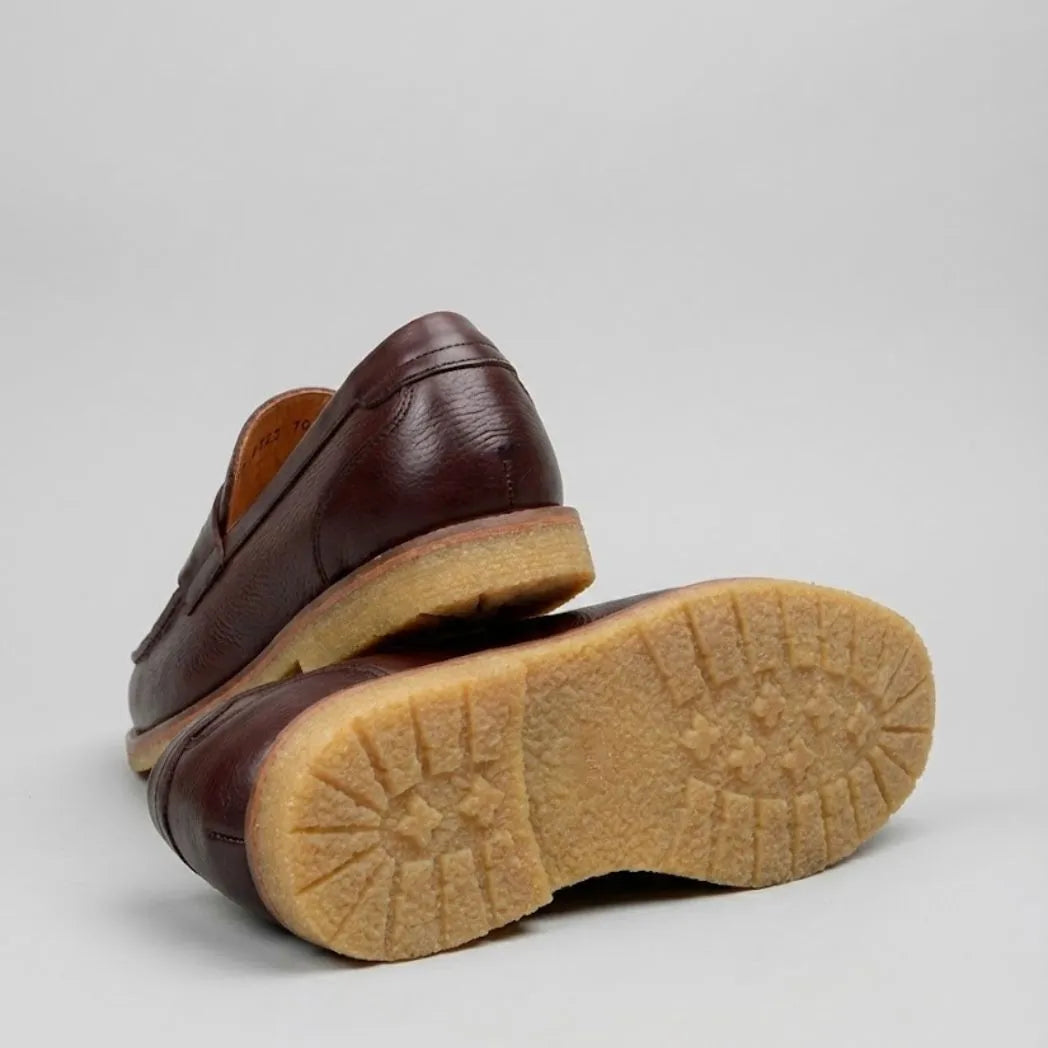 Mocassim Masculino Loafer Atenas: par marrom-escuro com um sapato virado, mostrando a sola bege com relevo.