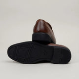 Mocassim Masculino Loafer Milan de Couro: par marrom com um sapato virado, mostrando a sola preta com sulcos.