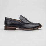Mocassim Masculino Paris Loafer de Couro: modelo preto de perfil, com faixa frontal, salto marrom e borda marrom na sola.