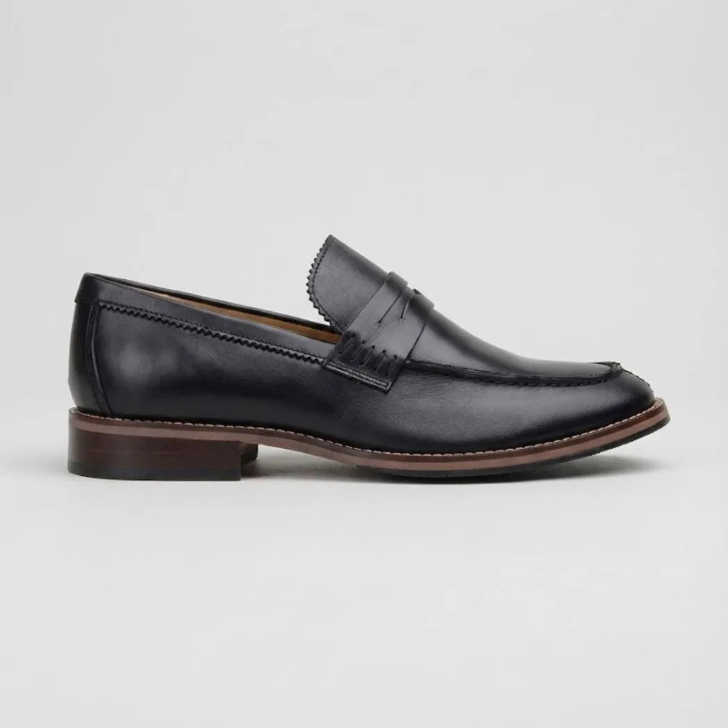 Mocassim Masculino Paris Loafer de Couro: modelo preto de perfil, com faixa frontal, salto marrom e borda marrom na sola.