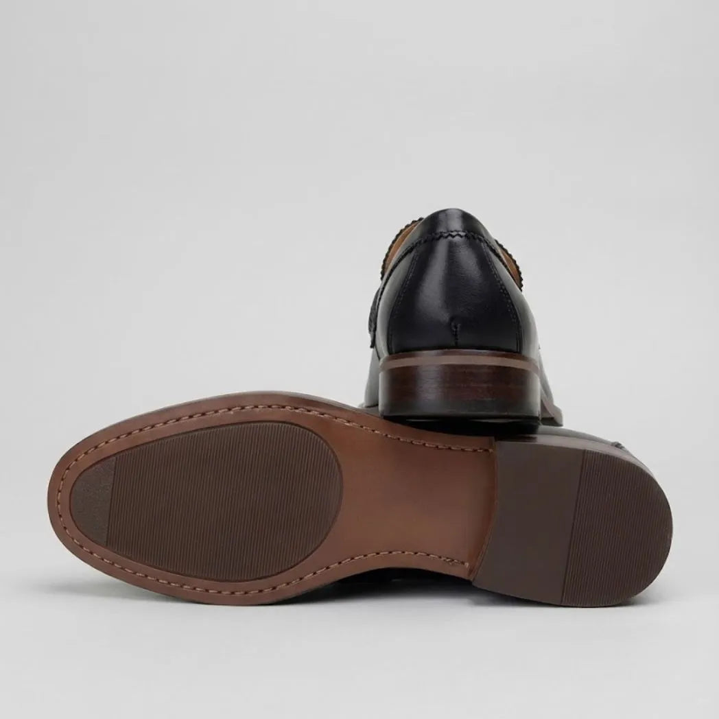 Mocassim Masculino Paris Loafer de Couro: par preto com um sapato virado, mostrando a sola marrom.