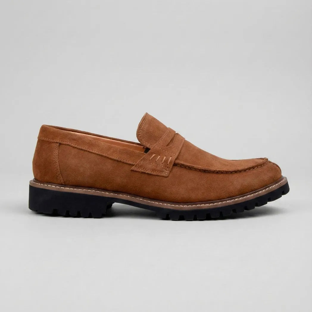 Mocassim Masculino Siena Loafer Camurça: modelo marrom de perfil, com faixa frontal e sola preta com sulcos profundos.