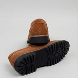 Mocassim Masculino Siena Loafer Camurça: par marrom com um sapato virado, mostrando a sola preta com sulcos profundos.