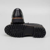 Mocassim Masculino Siena Loafer de Couro: par preto com um sapato virado, mostrando a sola preta com sulcos profundos.