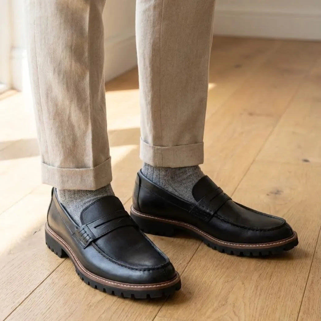Mocassim Masculino Siena Loafer de Couro: par preto com borda marrom na sola usado com calça clara dobrada na barra.