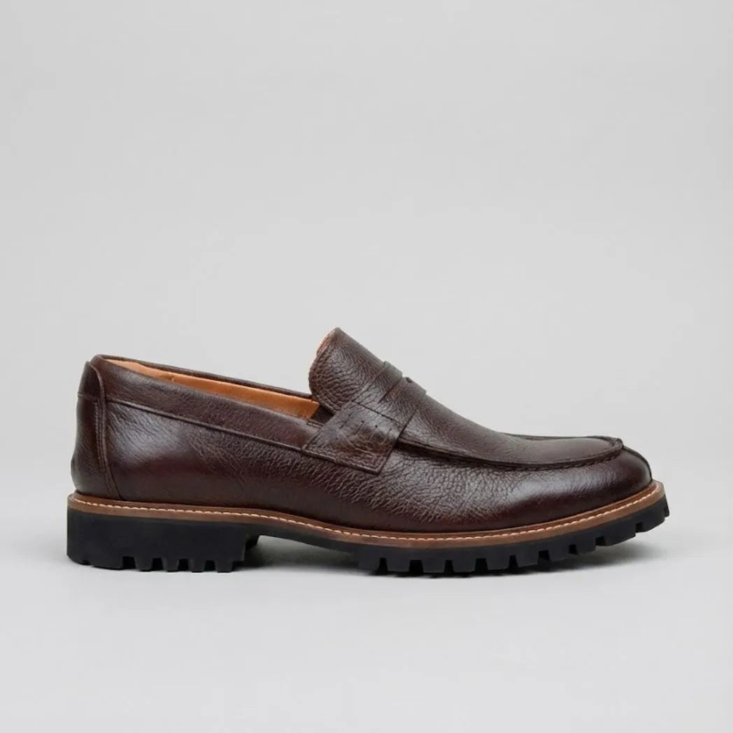 Mocassim Masculino Siena Loafer de Couro: modelo marrom-escuro de perfil, com faixa frontal, sola preta e borda marrom.
