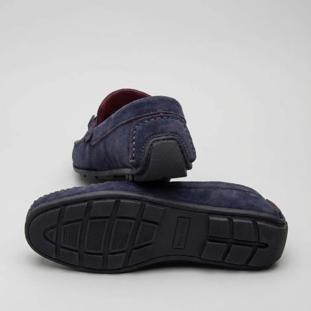 Par do modelo Mocassim Milano Driver com Fivela, na cor azul-escuro, com um dos solados voltado para a câmera.