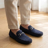 Mocassim Milano Driver com Fivela na cor azul-escuro, usado com calça clara de barra dobrada.