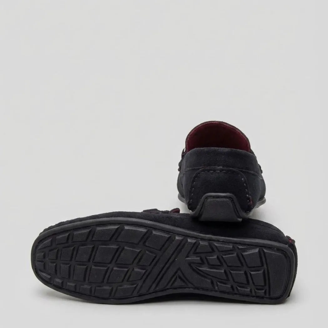 Par do modelo Mocassim Milano Driver com Fivela, na cor preto, com um dos solados voltado para a câmera.