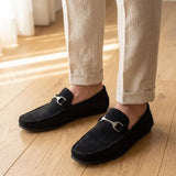 Mocassim Milano Driver com Fivela na cor preto, usado com calça clara de barra dobrada.