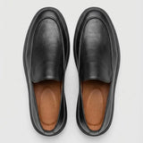 Mocassim Minimalista de Couro: par preto visto de cima, mostrando a parte frontal sem faixa e o interior marrom.
