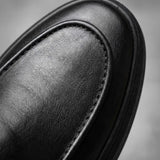 Mocassim Minimalista de Couro: detalhe da superfície preta e da costura no contorno da parte frontal.