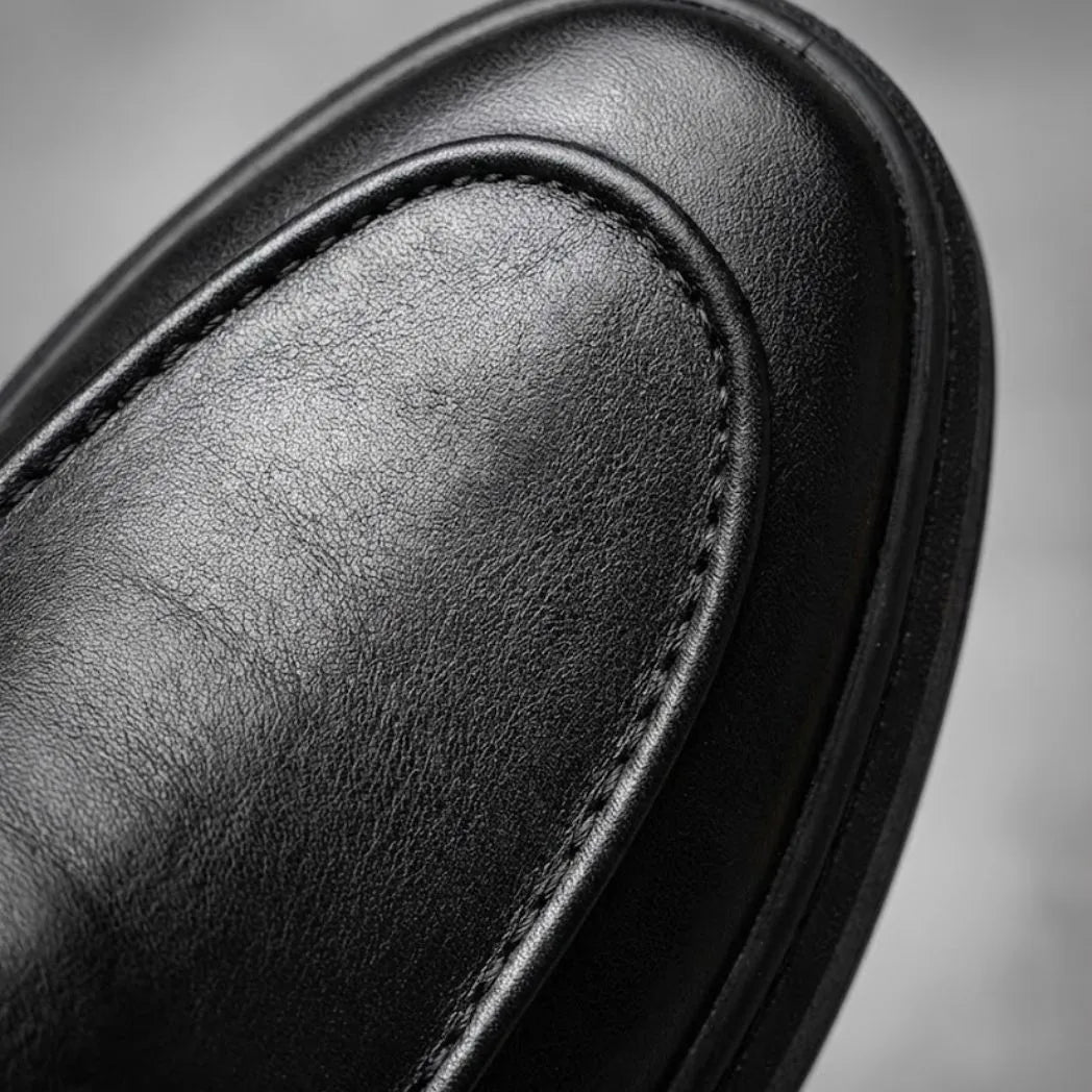 Mocassim Minimalista de Couro: detalhe da superfície preta e da costura no contorno da parte frontal.