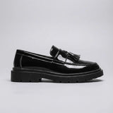Mocassim Obsidian de Couro: modelo preto brilhante de perfil, com enfeites de franjas e sola preta de sulcos profundos.
