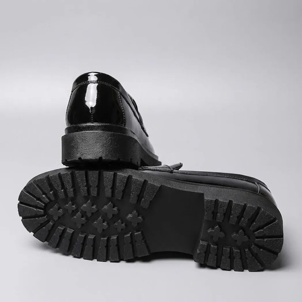 Par do modelo Mocassim Obsidian de Couro, na cor preto, com um dos solados voltado para a câmera.
