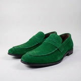 Mocassim Penny Loafer Milano Cognac: par verde em vista diagonal, com faixa frontal e sola preta.