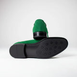 Par do modelo Mocassim Penny Loafer Milano Cognac, na cor verde, com um dos solados voltado para a câmera.