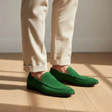 Mocassim Penny Loafer Milano Cognac: par verde usado com calça clara dobrada na barra.