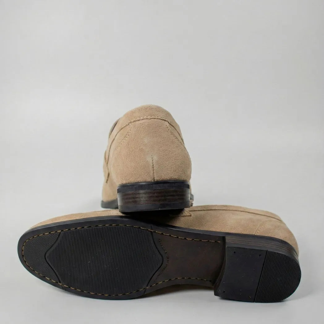 Mocassim Penny Loafer Milano Cognac: par bege com um sapato virado, mostrando a sola preta.