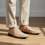 Mocassim Penny Loafer Milano Cognac: par bege usado com calça clara dobrada na barra.