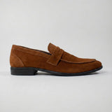 Mocassim Penny Loafer Milano Cognac: modelo marrom de perfil, com faixa frontal e sola preta.