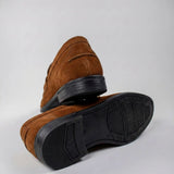 Mocassim Penny Loafer Milano Cognac: par marrom com um sapato virado, mostrando a sola preta.