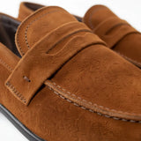 Mocassim Penny Loafer Milano Cognac: detalhe da textura marrom, da faixa frontal e da costura.