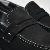 Mocassim Penny Loafer Milano Cognac: detalhe da faixa frontal preta e da costura clara na parte frontal.