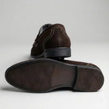 Mocassim Penny Loafer Milano Cognac: par marrom-escuro com um sapato virado, mostrando a sola escura.