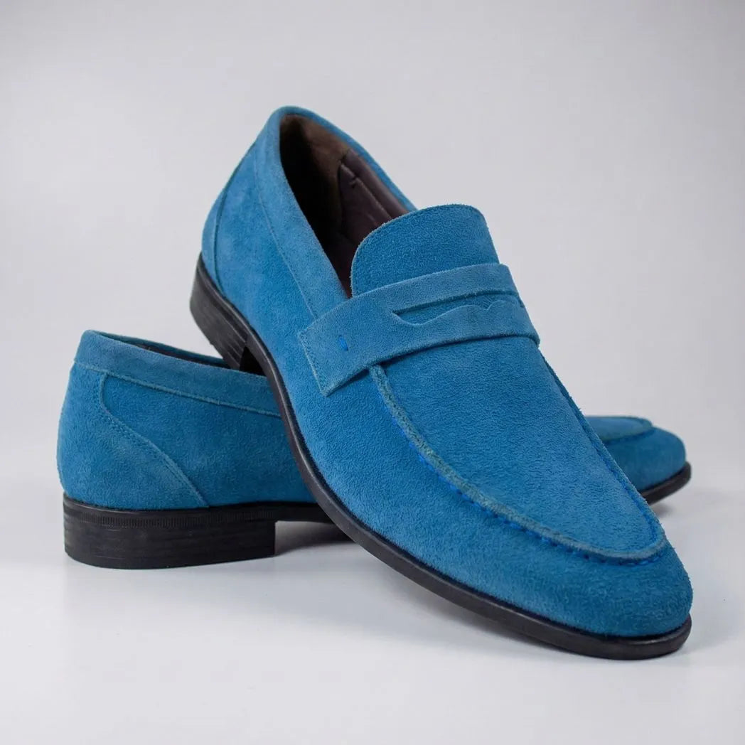 Mocassim Penny Loafer Milano Cognac: par azul em posição cruzada, com faixa frontal e sola preta.