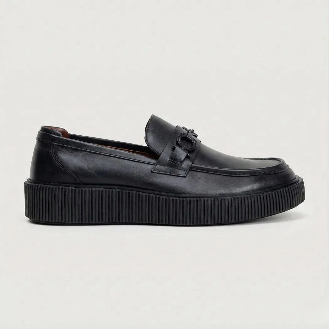 Mocassim Plataform com Fivela: modelo preto de perfil, com ferragem frontal escura e sola preta espessa de borda estriada.