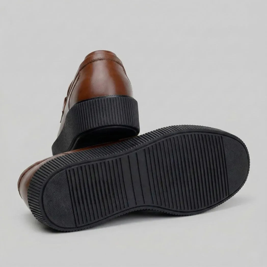 Par do modelo Mocassim Plataform com Fivela, na cor marrom, com um dos solados voltado para a câmera.