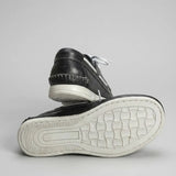 Mocassim Sider de Couro: par preto com um sapato virado, mostrando a sola clara com relevo.