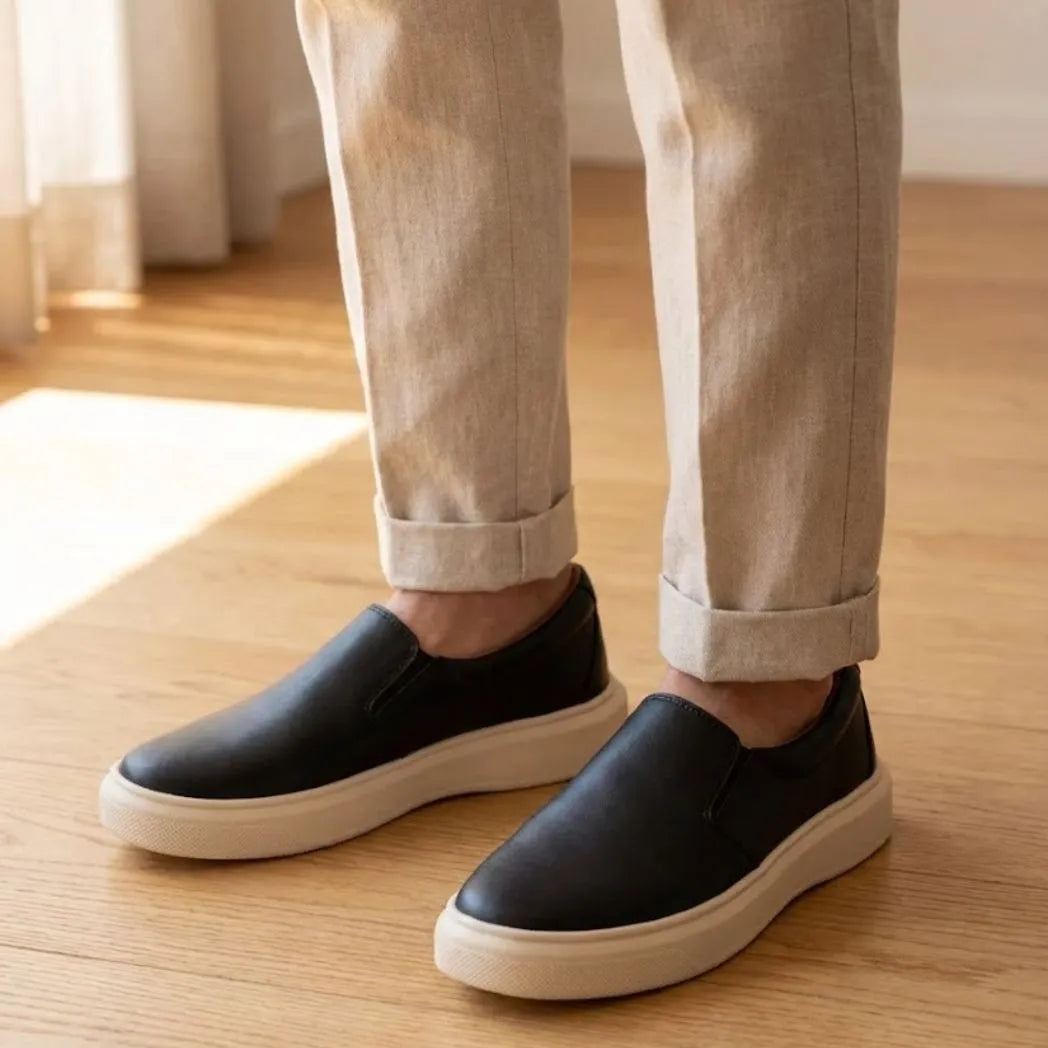 Mocassim Slip On Casual de Couro: par preto com sola bege usado com calça clara dobrada na barra.