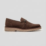 Mocassim Suede Tratorado de Camurça: modelo marrom de perfil, com pequena ferragem frontal e sola bege com sulcos.