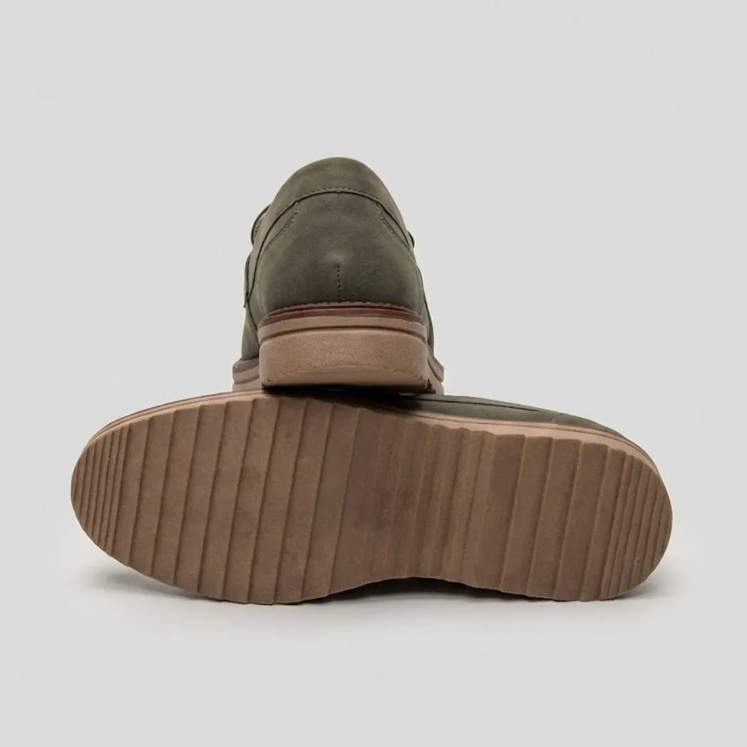 Par do modelo Mocassim Suede Tratorado de Camurça, na cor verde, com um dos solados voltado para a câmera.