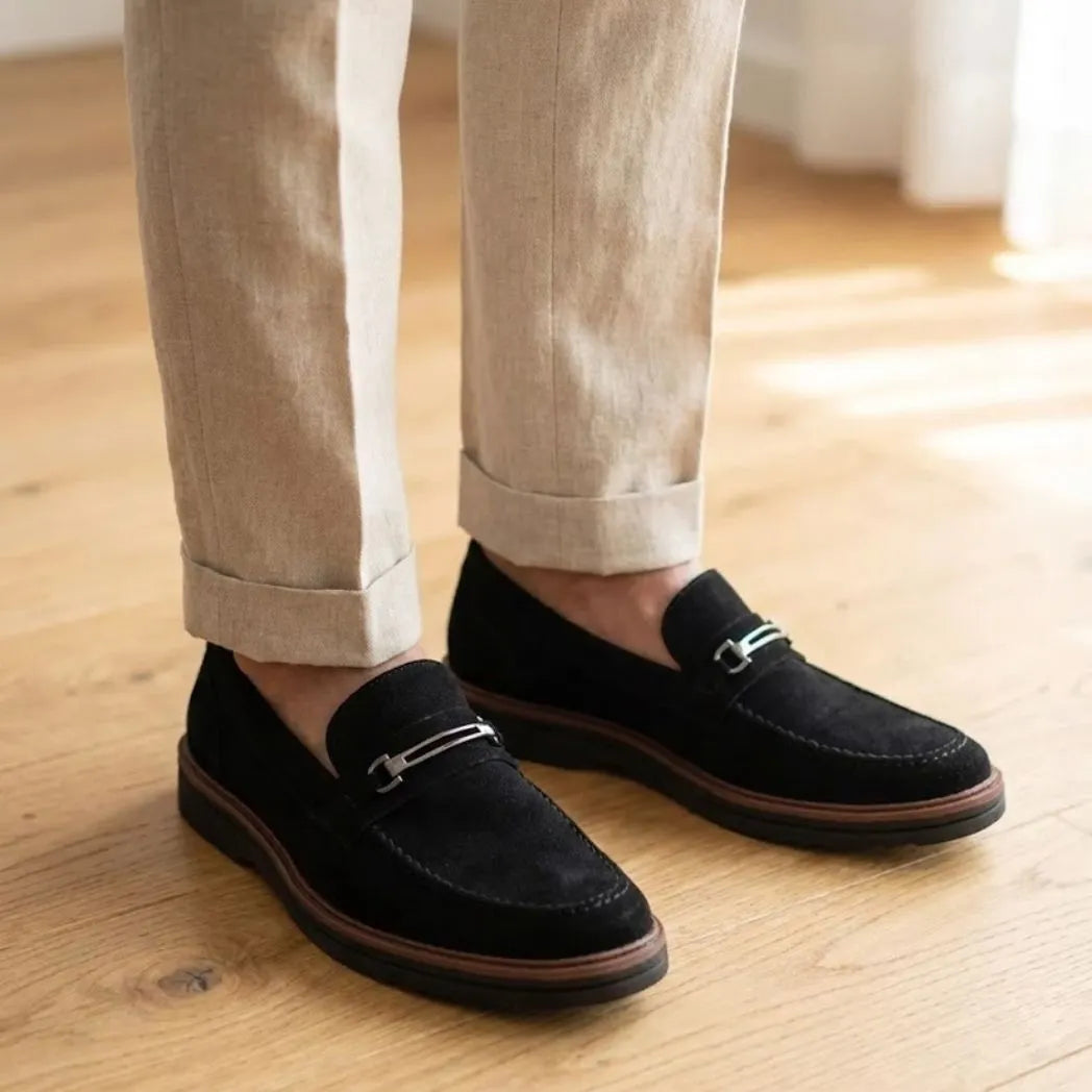 Mocassim Suede Tratorado de Camurça na cor preto, usado com calça clara de barra dobrada.