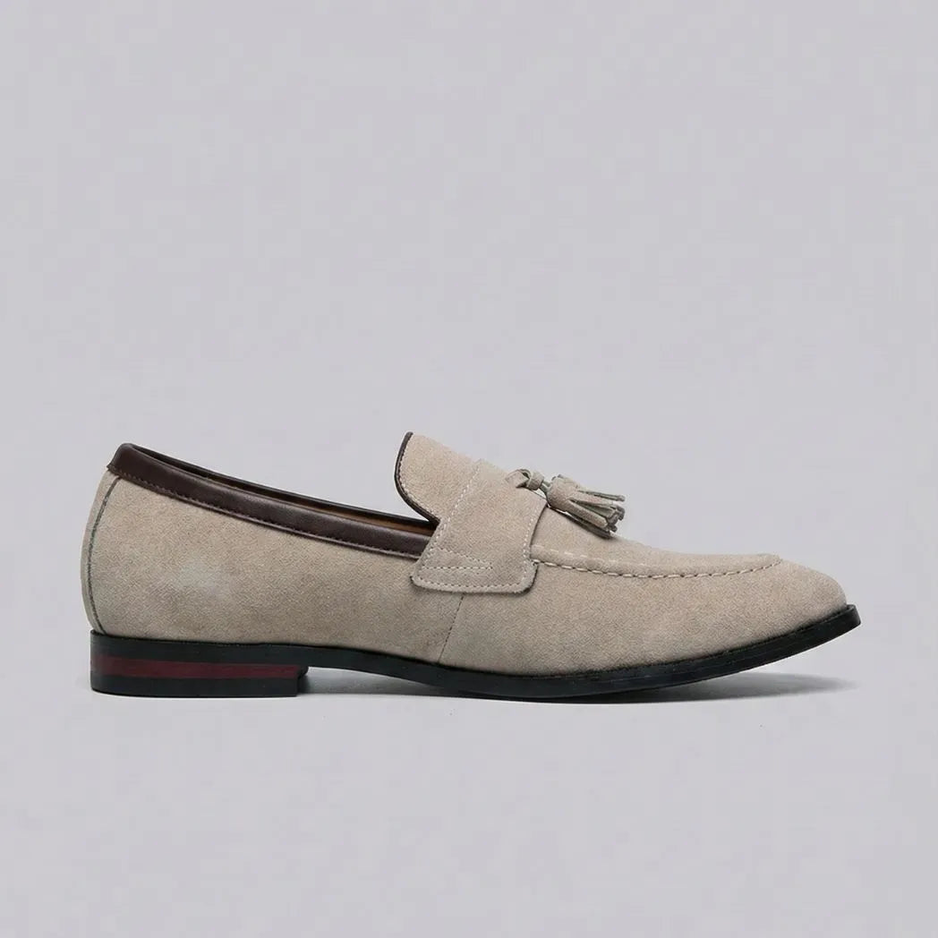 Mocassim Tassel de Camurça Premium: modelo bege de perfil, com enfeite de franjas e detalhe vermelho no salto.