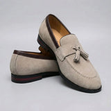 Mocassim Tassel de Camurça Premium: par bege em posição cruzada, com destaque para os enfeites de franjas na parte frontal.