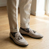 Mocassim Tassel de Camurça Premium: par bege com enfeites de franjas usado com calça clara dobrada na barra.