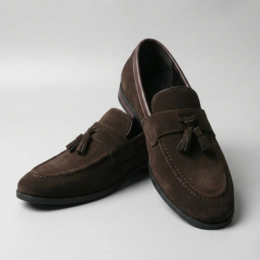 Mocassim Tassel de Camurça Premium: par marrom em posição cruzada, com enfeites de franjas na parte frontal.