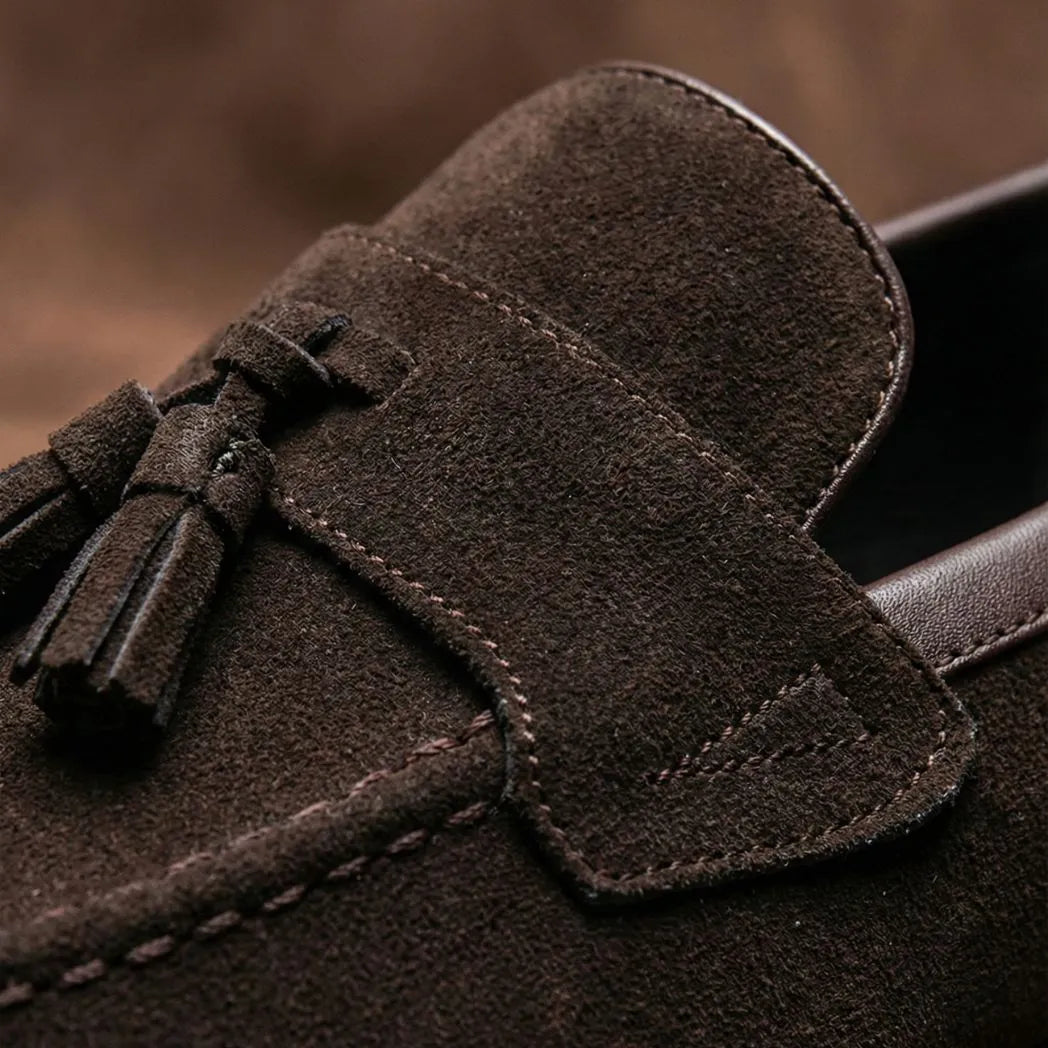 Mocassim Tassel de Camurça Premium: detalhe dos enfeites de franjas e da textura marrom na parte frontal.