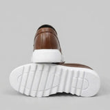 Par do modelo Mocassim Torino Ripple Tratorado de Couro, na cor marrom, com um dos solados voltado para a câmera.