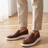 Mocassim Torino Ripple Tratorado de Couro na cor marrom, usado com calça clara de barra dobrada.