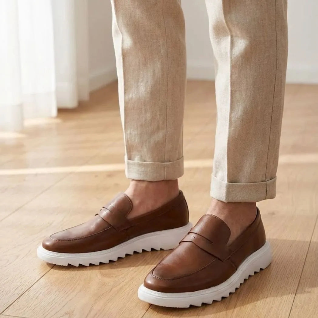 Mocassim Torino Ripple Tratorado de Couro na cor marrom, usado com calça clara de barra dobrada.