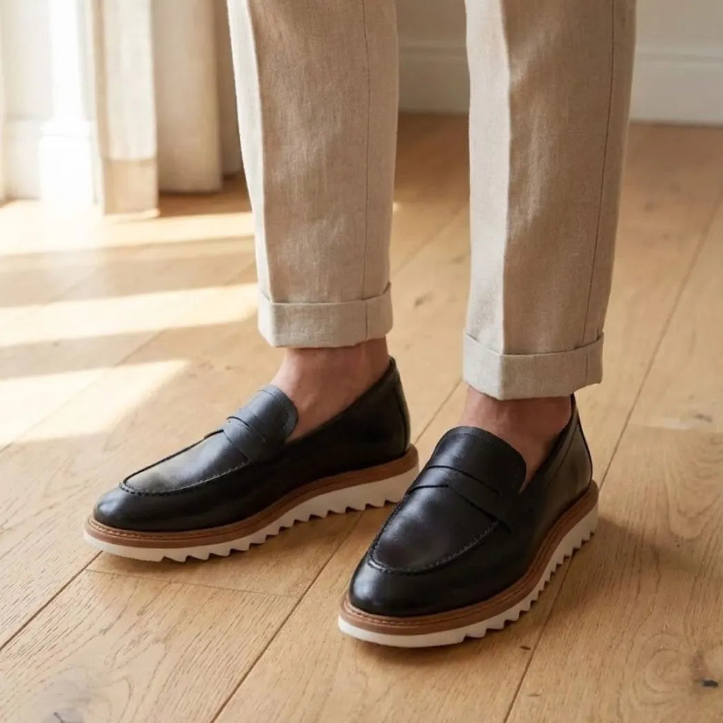 Mocassim Tratorado Milano de Couro na cor preto, usado com calça clara de barra dobrada.