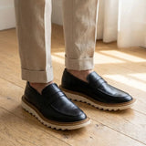 Mocassim Tratorado Siena Ripple na cor preto, usado com calça clara de barra dobrada.